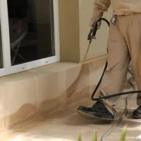 General pest control technician spraying exterior perimeter around a home in Grand Rapids, MI