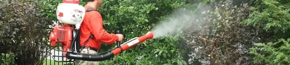 Mosquito control technician fogging shrubs and landscaping for mosquito treatment in Grand Rapids, MI